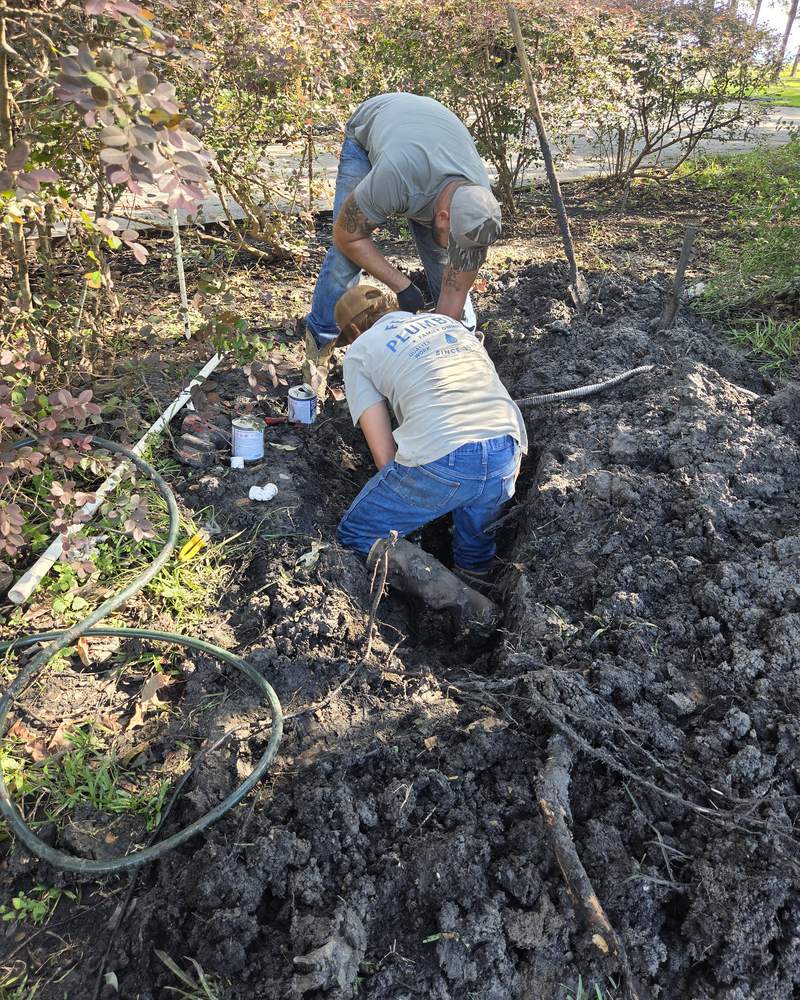 Two Festus Plumbing plumbers digging out a line in a customer's yard, one wearing a Festus Plumbing shirt